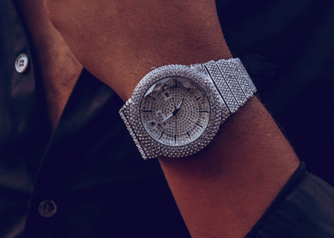 Iced-out diamond-set luxury watch worn on wrist
