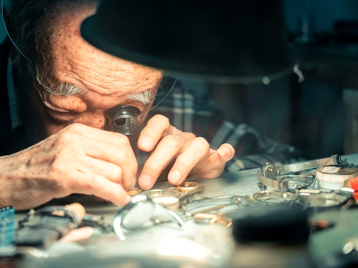 Watchmaker inspecting wristwatch details with a loupe